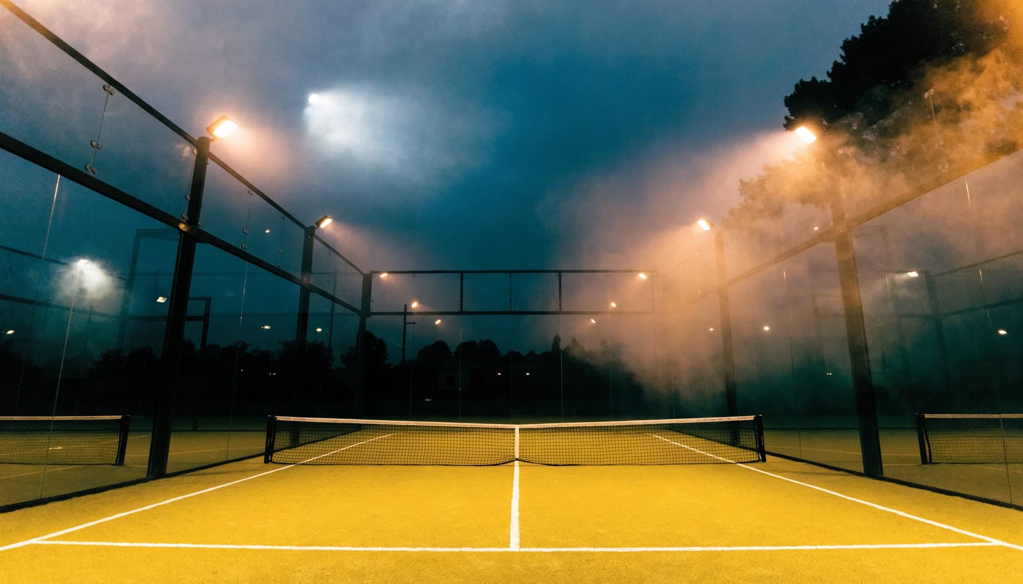 Padel court seen through its glass wall at blue hour
