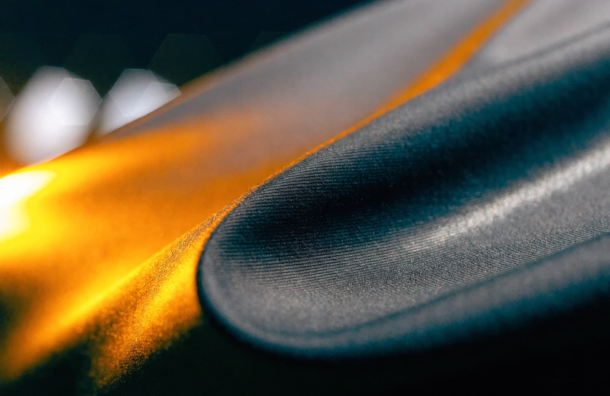 Macro study of dark technical fabric catching one warm light