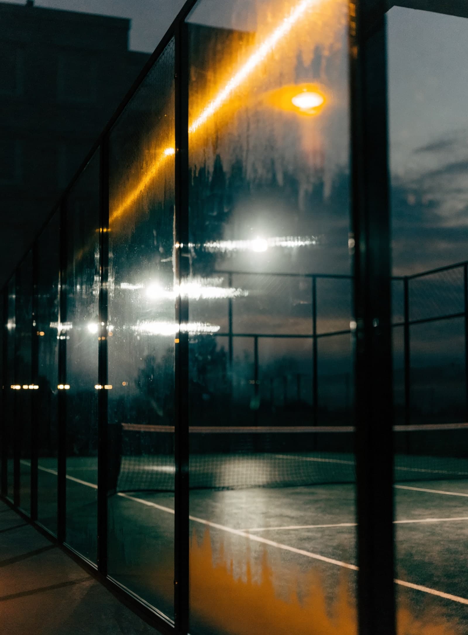 Empty padel court under a single floodlight at night